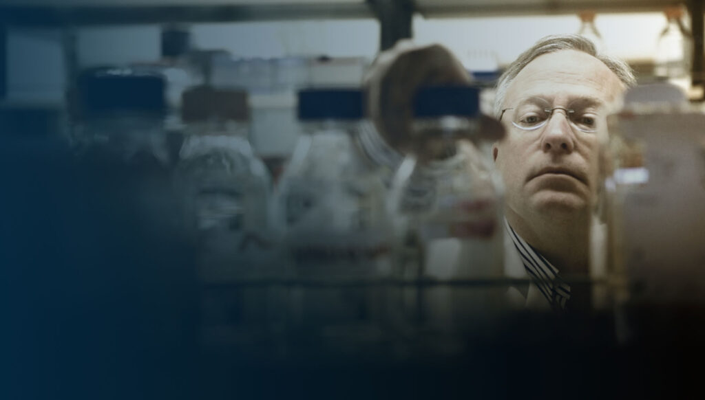 Dr. Lynch picks up a glass beaker from a laboratory shelf