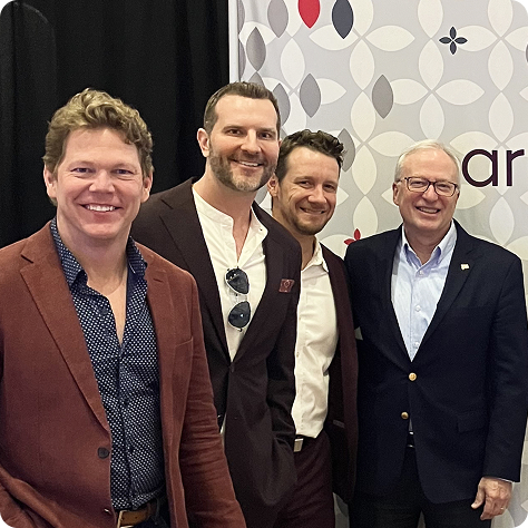 Four people standing and smiling in front of an ariessence pure PDGF+ conference booth display