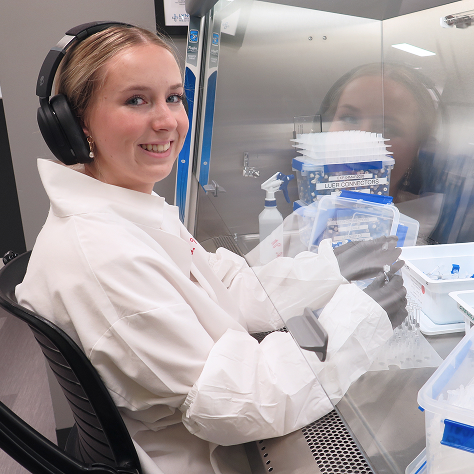 A scientist working in a lab, smiling at the viewer