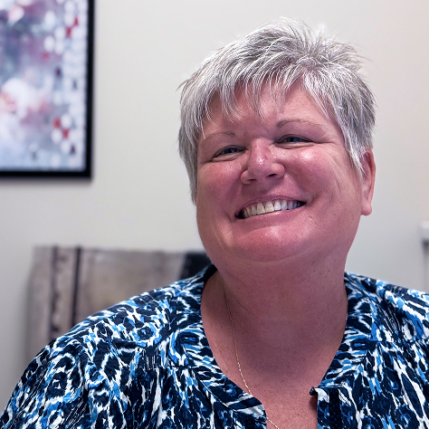 A woman smiling in an office at the viewer
