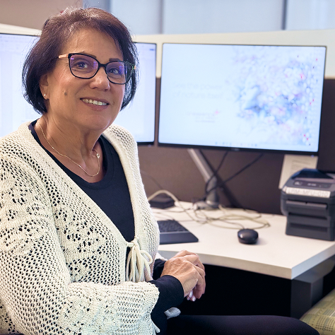 A woman sitting at a computer desk, smiling at the viewer