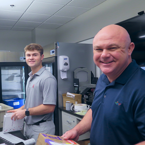 Two men working in an office, smiling at the viewer
