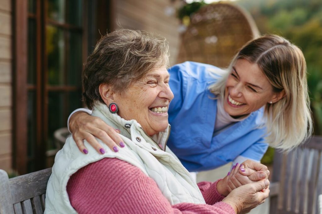 A nurse laughing and smiling with an older woman