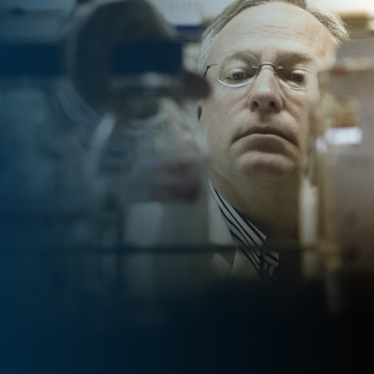 Dr. Lynch picks up a glass beaker from a laboratory shelf